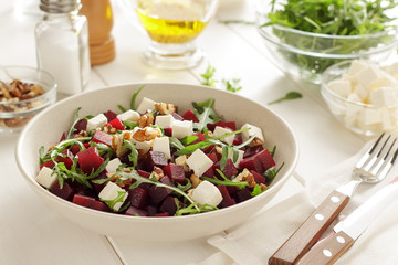 Salad with beet, feta, arugula and walnuts in the ceramic bowl.