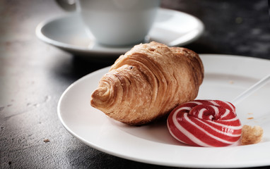 Croissant on plate close up. Morning coffee in a cup.