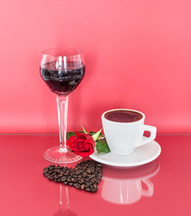 A cup of fresh coffee, a glass of wine and coffee beans arranged in a heart shape on the glass table