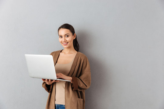 Portrait Of A Happy Young Asian Woman Holding Laptop