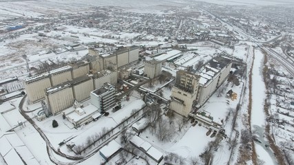 Grain terminal in the winter season. Snow-covered grain elevator in rural areas. A building for drying and storing grain