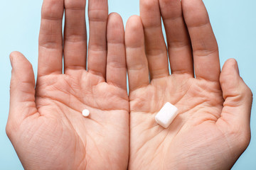 Choice of Sweetener in tablets or regular sugar. Alternative to sugar for diabetics. A man holds sugar in one hand in another sugar sauce in tablets.