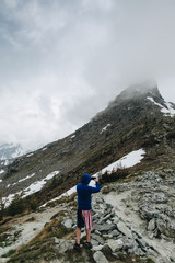 Naklejka premium Hiker with short pant American Flag Taking photo with his smart phone to the panorama in the mountain.