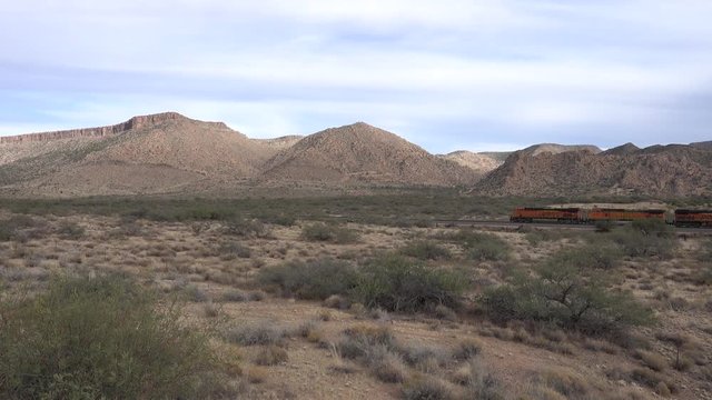 A freight train passes from right to left in the desert on a dry hill background- Un train de marchandise passe de droite &agrave; gauche dans le d&eacute;sert sur fond de colline aride