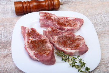 Raw pork chops and spice grinder on cutting board. Ready for cooking.