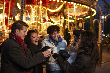 Group Of Friends Drinking Mulled Wine At Christmas Market