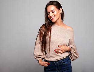 Obraz premium Portrait of beautiful smiling cute brunette woman model in casual beige warm sweater clothes with no makeup isolated on gray