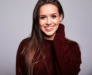 Portrait of beautiful happy cute brunette woman model in casual warm red sweater clothes isolated on gray with no makeup