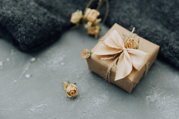 Wrapped gift box with dry flowers over blue background 