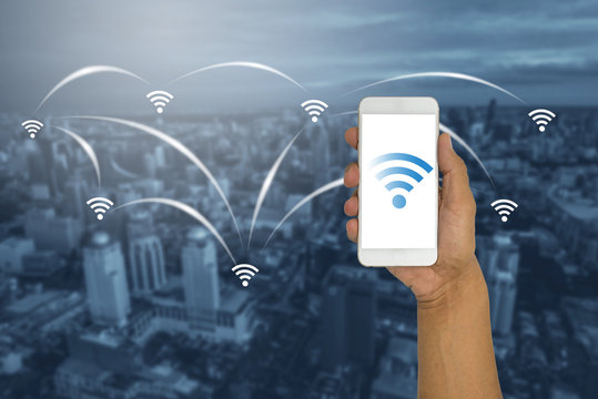 Hand holding a phone with wifi logo on a city background with connexions