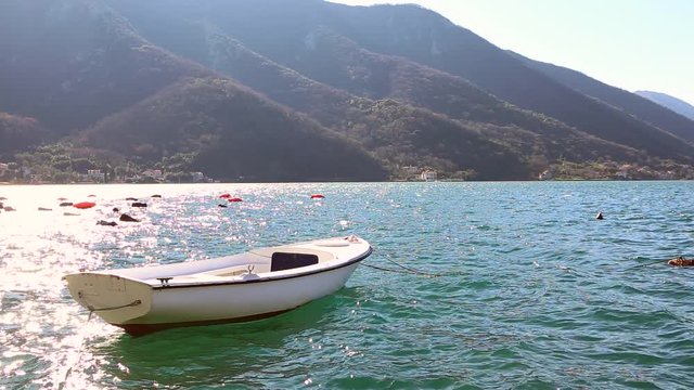 White fishing boat rocks on the waves. Sunny day. Montenegro, Kotor Bay. Slow motion