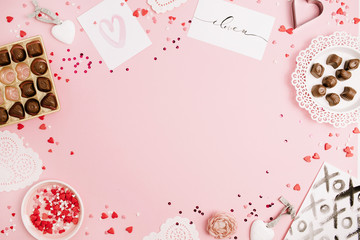 Valentine's Day, love concept. Mock up frame made of confetti, heart symbol accessories, sweets, postcards on pink background. Flat lay, top view.