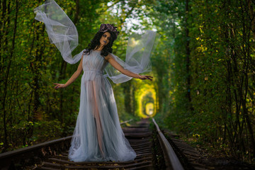 Obraz na płótnie Canvas make up of dead bride dressed in wedding clothes in the tunnel inside a forest with train rails