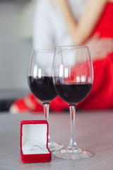 Photo of hugging beautiful couple. Glasses with wine and box with ring on table