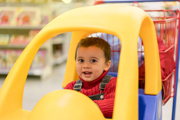Fototapeta na wymiar little cheerful boy in a trolley in a shopping center