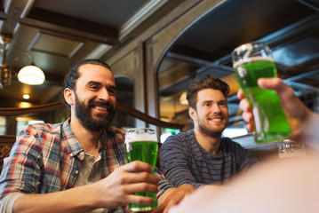 male friends drinking green beer at bar or pub