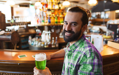 man drinking green beer at bar or pub