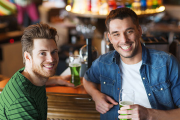 male friends drinking green beer at bar or pub