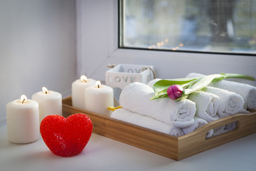 Fototapeta na wymiar the Rolled hand towels on a tray next to the lighted candles and a bouquet of tulips in the spa salon