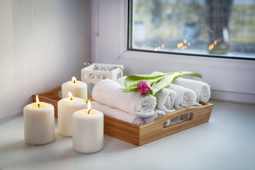 the Rolled hand towels on a tray next to the lighted candles and a bouquet of tulips in the spa salon
