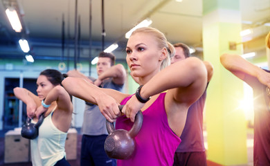 Fototapeta na wymiar group of people with kettlebells exercising in gym