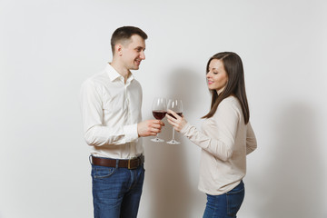Young caucasian couple. Happy smiling man and woman in love in casual light clothes, jeans making toast, drinking from glasses of red wine isolated on white background. Copy space for advertisement.