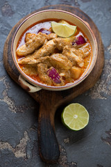 Bowl with chicken massaman curry on a wooden serving board, vertical shot, selective focus