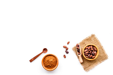 Main ingredient for chocolate. Cocoa powder in bowl near cocoa beans on white background top view copy space