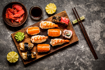 sushi and sushi rolls, sushi nigiri on stone plate on dark background, mustard wasabi, and ginger