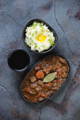 Traditional Irish beer and beef stew served with champ and dark beer for Saint Patrick’s Day, top view over grey asphalt background