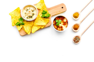 Middle Eastern cuisine. Bowl with hummus among pieces of crispbread and spices on white background top view copy space