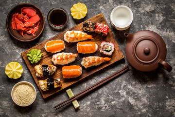 sushi and sushi rolls, sushi nigiri on stone plate on dark background, mustard wasabi, and ginger