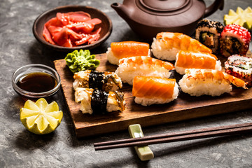 sushi and sushi rolls, sushi nigiri on stone plate on dark background, mustard wasabi, and ginger