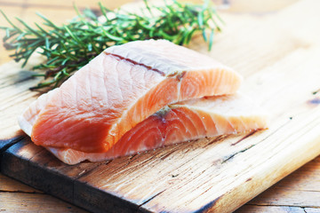 Salmon filet with fresh rosemary  on wooden board.