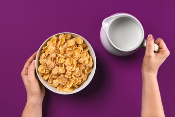 Fototapeta na wymiar Food and people concept - hands of woman eating cereals (corn flakes) for breakfast and pouring milk
