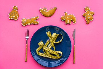 Sport and healthy diet for slimming. Plate, measuring tape and cookies in shape of yoga asans on pink background top view