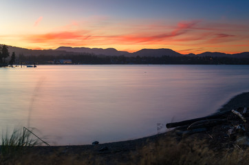 Spectacular sunset over a bay. Forested Mountain are Visible in Background. Sooke, Vancouver Island, BC, Canada.