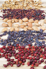 Different nuts, dog rose and raisins on a wooden board table