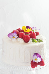 Festive cake with raspberries and flowers with streaks of glaze on  white background