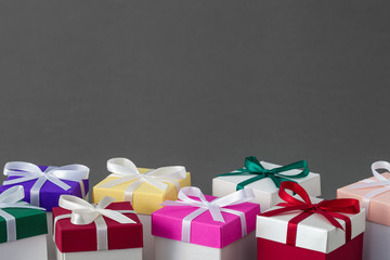 Several gift boxes with bright colorful lids and ribbons on gray background. Copy space for text.