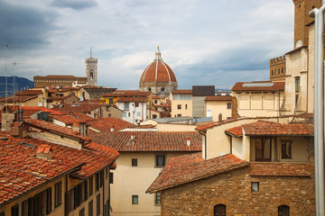 Fototapeta na wymiar The urban landscape of Florence. Top view of the Cathedral of Saint Mary of the Flower and the tiled roofs of houses. Brick Dome of the Duomo over the roofs of the city. June 2017.