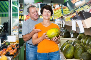 Fototapeta premium Adult man and his wife are choosing ripe melon