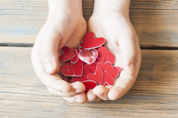 red hearts in hands closeup on wooden background