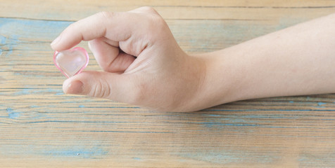 red hearts in hands closeup on wooden background