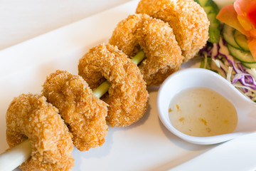 Deep fried shrimp in white plate with plum sauce on the stone table.