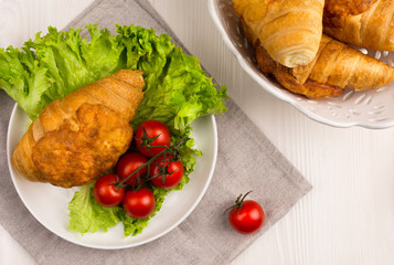 Cheese croissant on a plate with lettuce leaves and cherry tomatoes