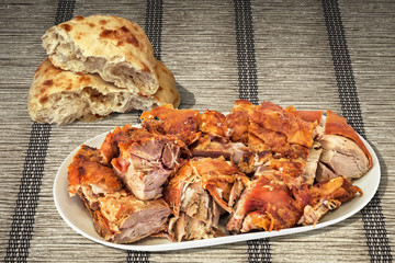 Plateful Of Freshly Spit Roasted Pork Shoulder Slices And Leavened Pitta Flatbread Torn Loaf Set On Plaited Interlaced Ocher Paper Parchment Place Mat