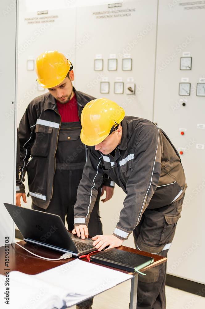 Wall mural field service engineers inspect relay protection system with laptop computer