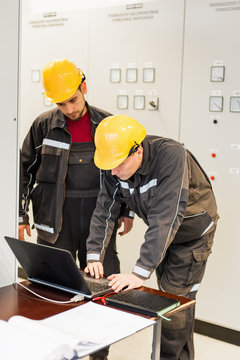 Field service engineers inspect relay protection system with laptop computer