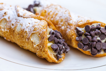 Italian cannoli on white plate with blackberries and chocolate chips - obrazy, fototapety, plakaty